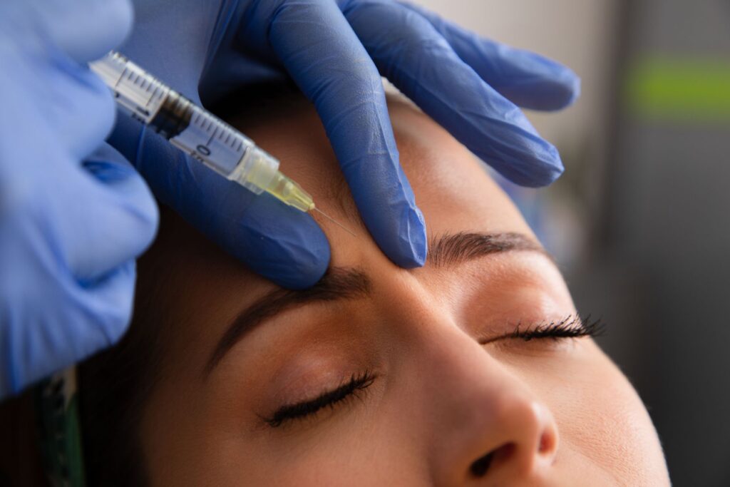 a female patient with closed receiving a botox injection between her eyebrows